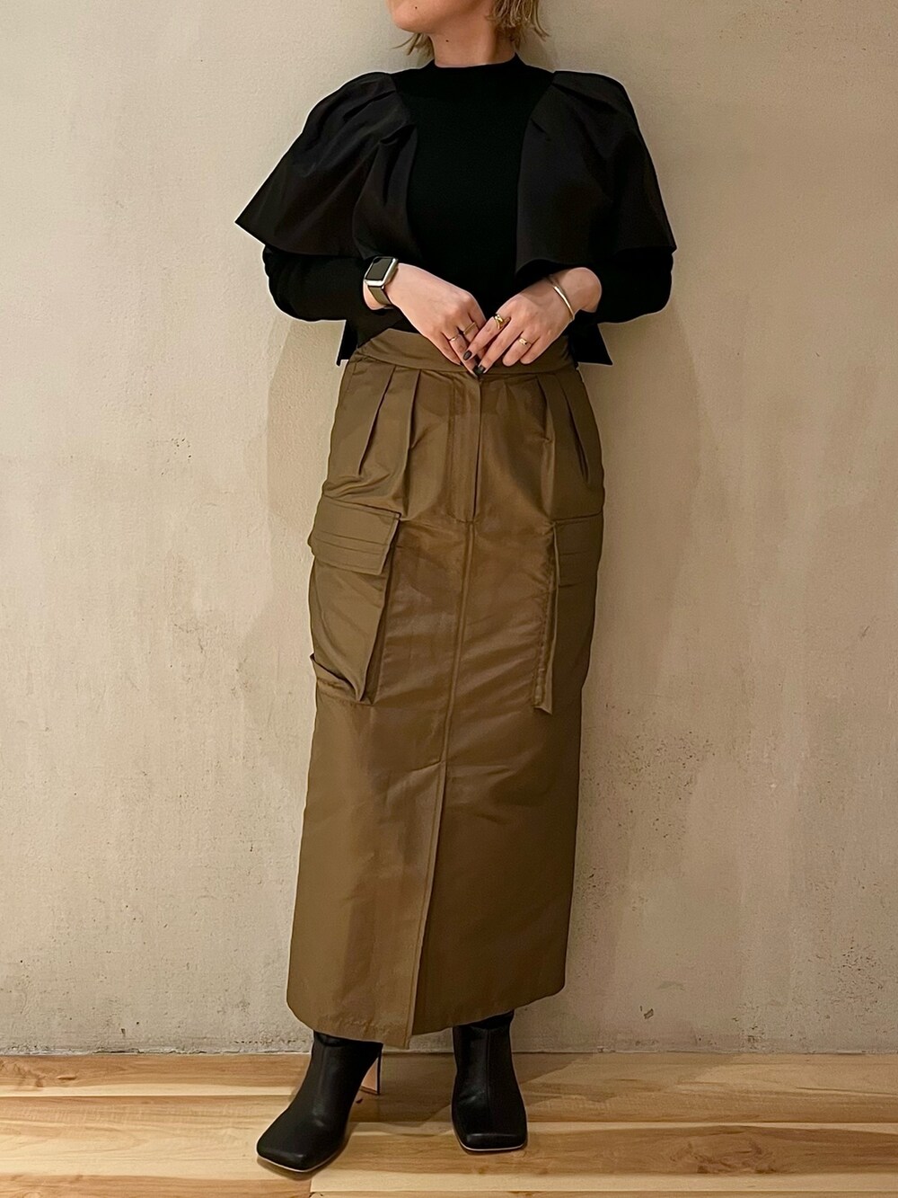 ブラウン系のスカート、ブラック系のブーツ、ブラック系のニット/セーターを着用したレディースの春コーディネートの5枚目の写真