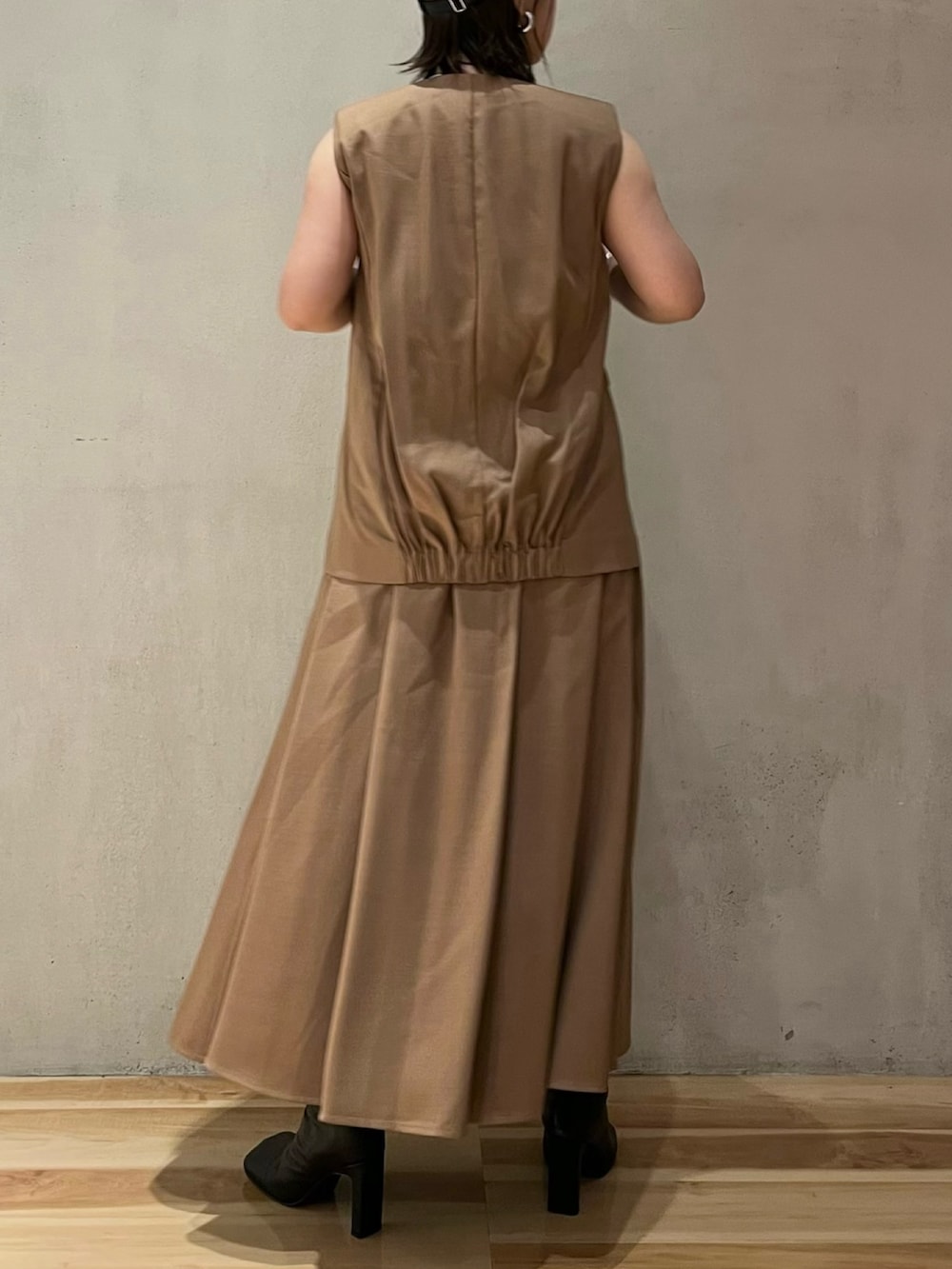 ベージュ系のワンピース、ブラック系のブーツ、ブラック系のキャップを着用したレディースの夏コーディネートの2枚目の写真