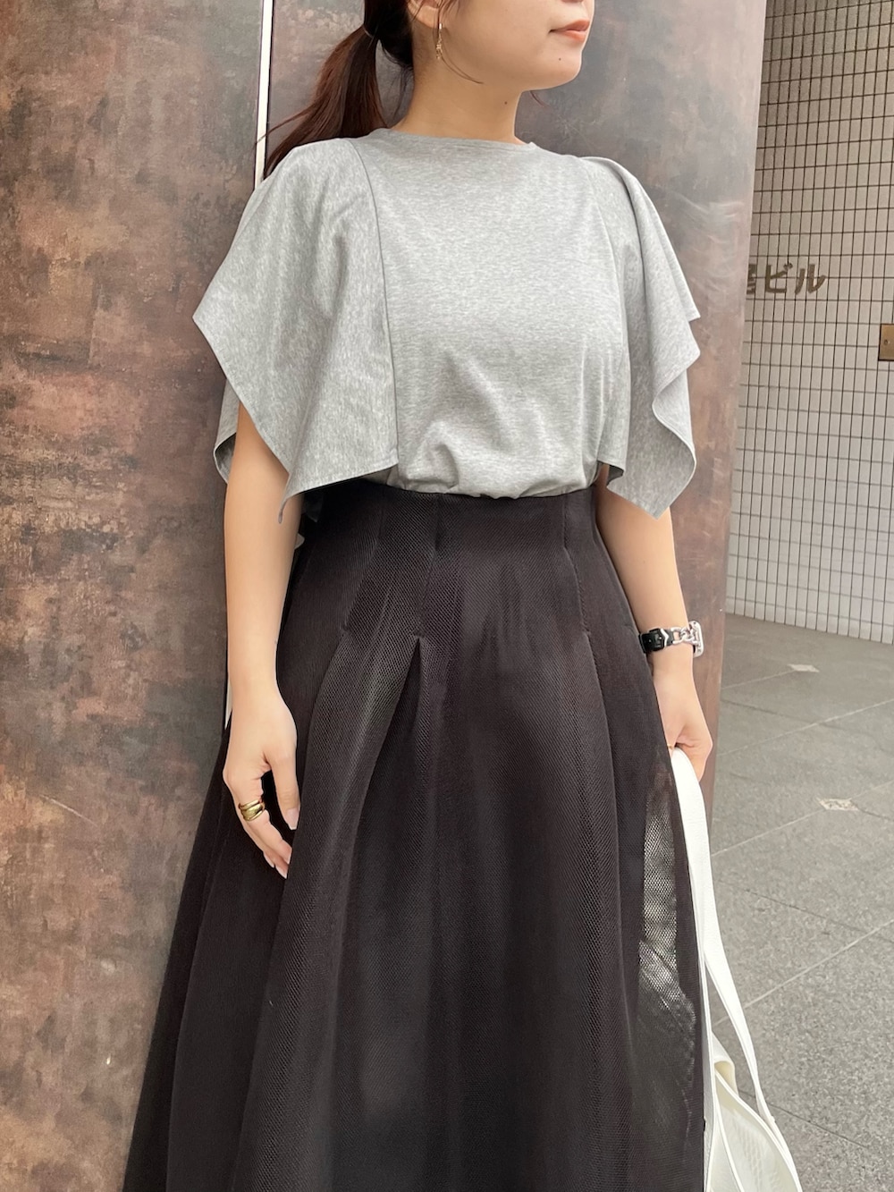 グレー系のTシャツ/カットソー、ブラック系のスカート、ブラック系のパンプスを着用したレディースの春コーディネートの4枚目の写真