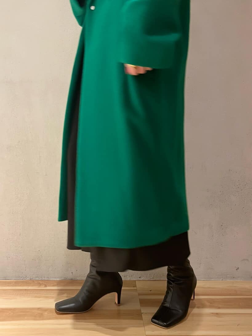 ブラック系のジャンパースカート、ブラウン系のニット/セーター、グリーン系のチェスターコートを着用したレディースの秋コーディネートの7枚目の写真