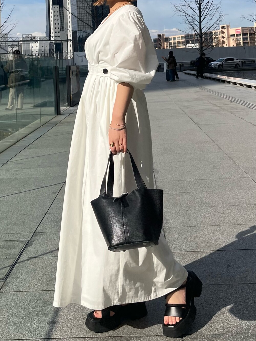 ブラック系のサンダル、ホワイト系のワンピース、ブラック系のハンドバッグを着用したレディースの冬コーディネートの2枚目の写真