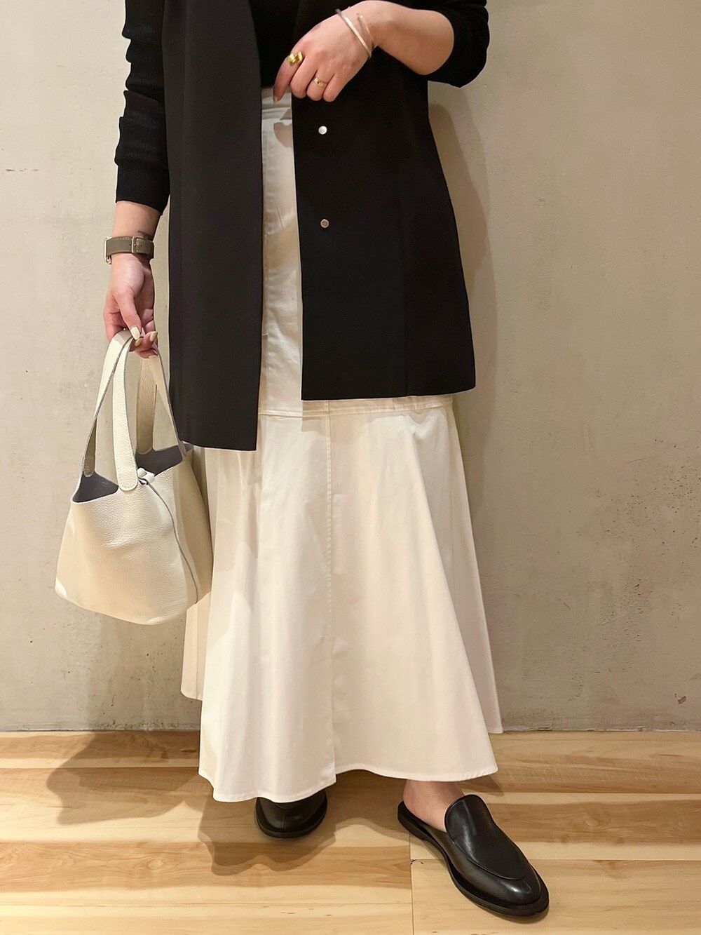 ホワイト系のスカート、ホワイト系のハンドバッグ、ブラック系のテーラードジャケットを着用したレディースの冬コーディネートの7枚目の写真
