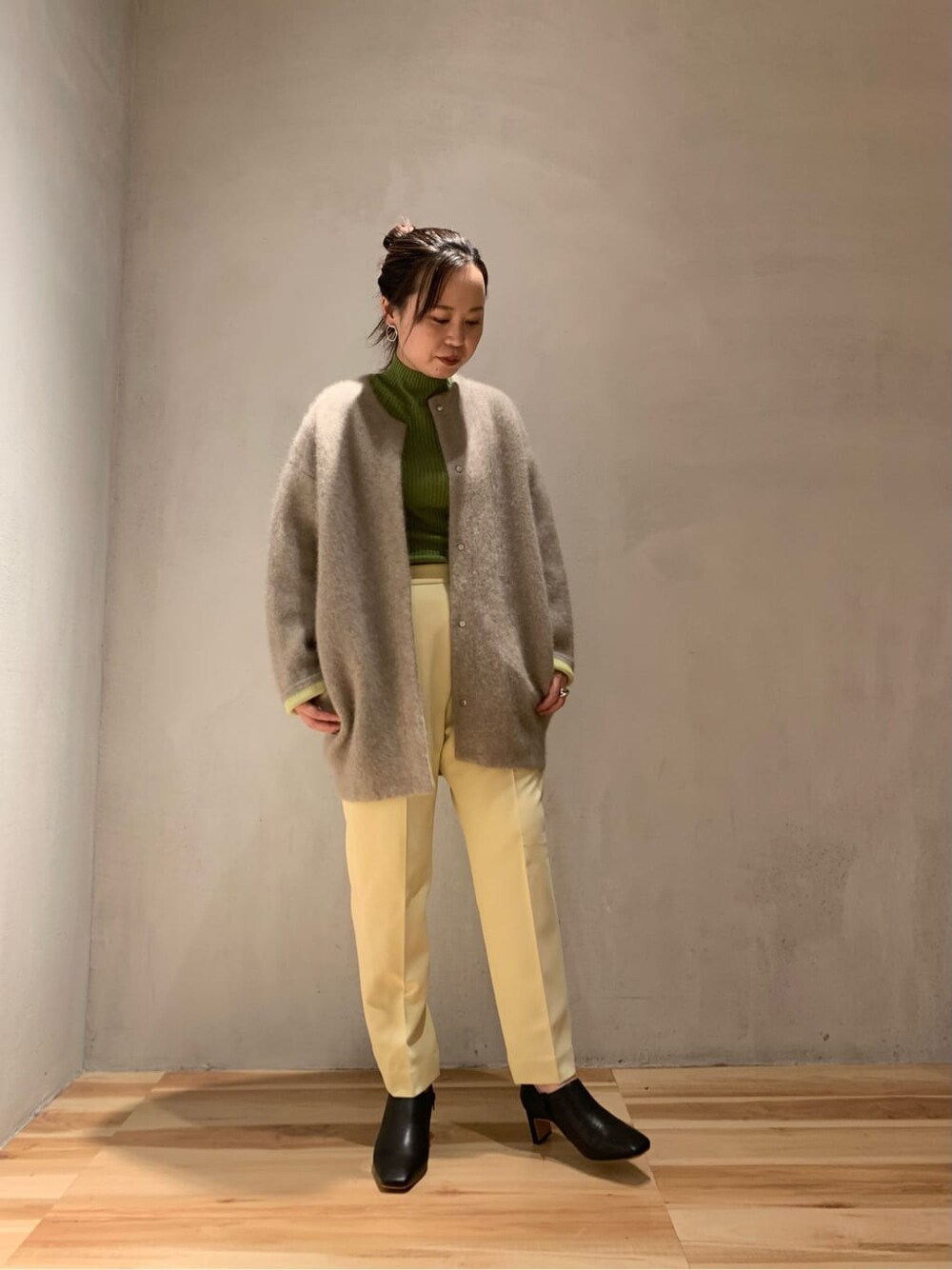 ブラック系のブーツ、イエロー系のスラックス、ブラウン系のカーディガン/ボレロを着用したレディースの秋コーディネートの2枚目の写真