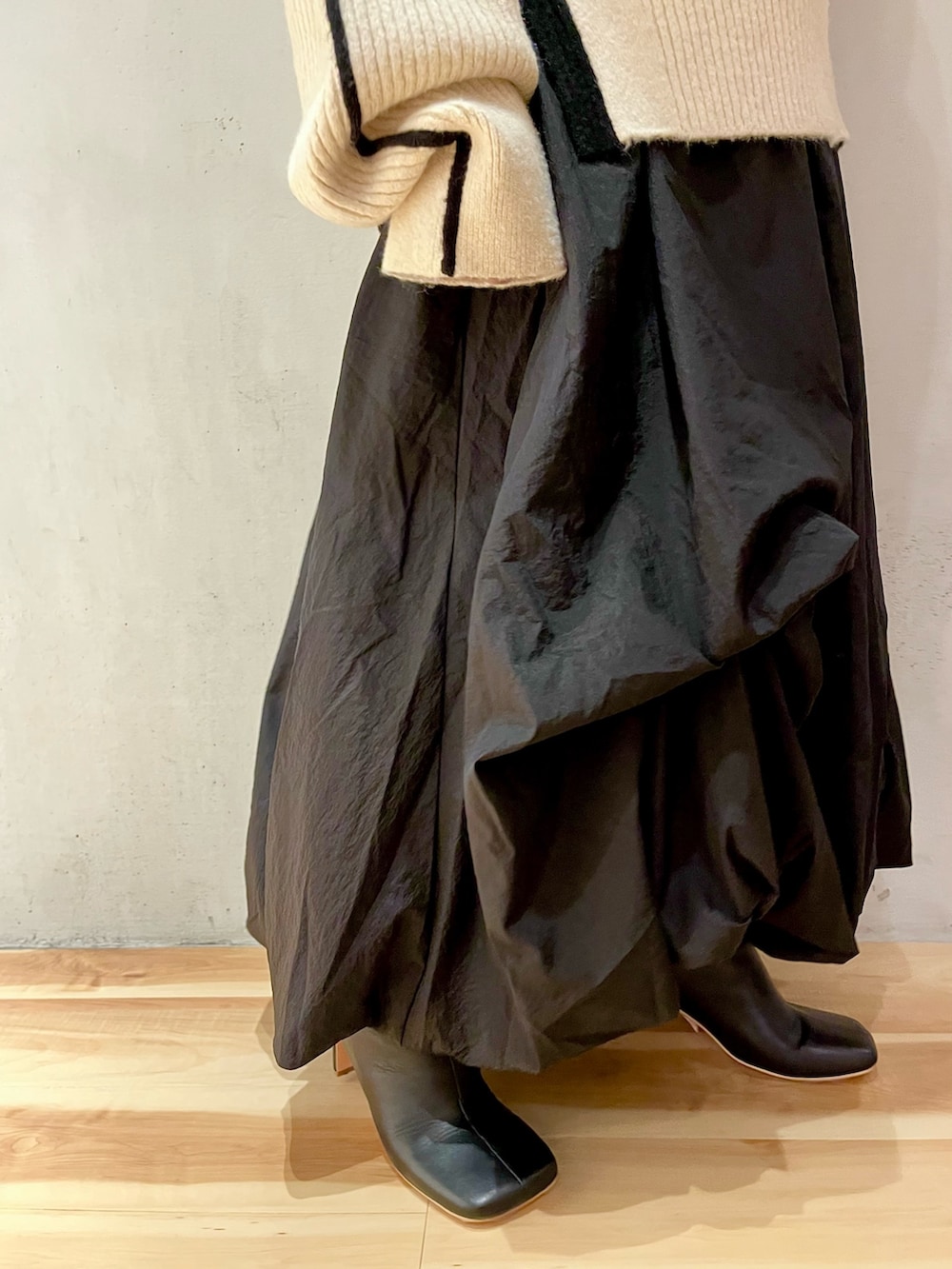 ブラック系のスカート、ホワイト系のニット/セーター、ブラック系のブーツを着用したレディースの秋コーディネートの8枚目の写真