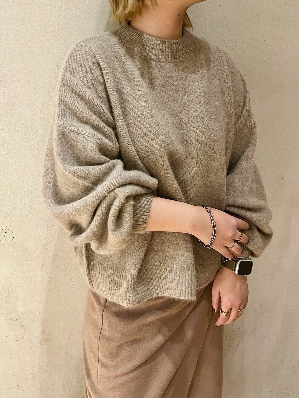 ベージュ系のニット/セーター、ベージュ系のスカート、ブラック系のブーツを着用したレディースの秋コーディネートの4枚目の写真