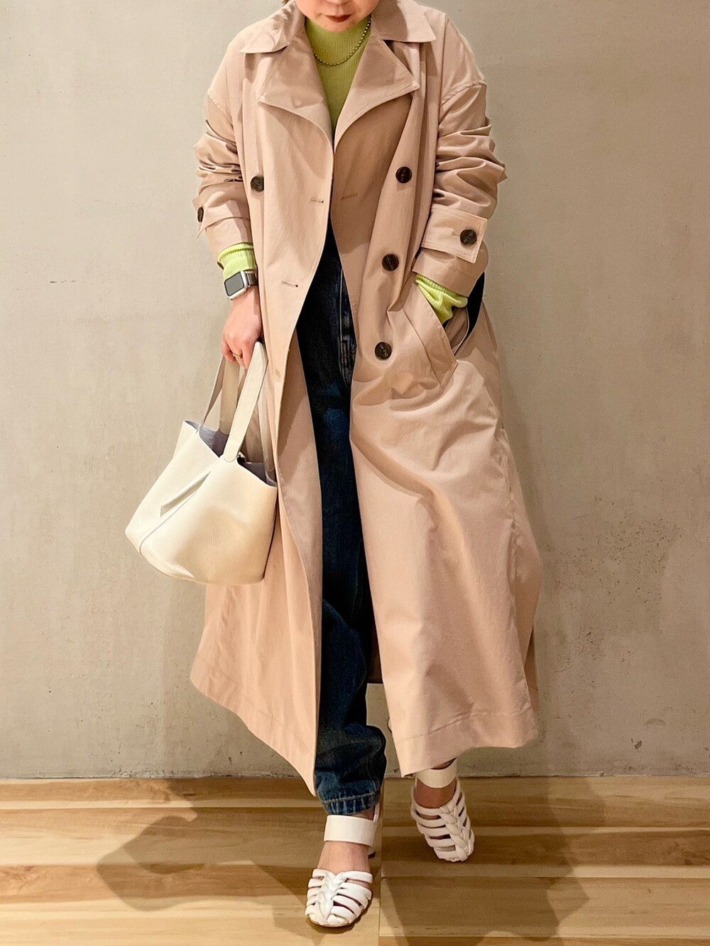 グリーン系のニット/セーター、ベージュ系のトレンチコート、ブルー系のデニムパンツを着用したレディースの冬コーディネートの4枚目の写真