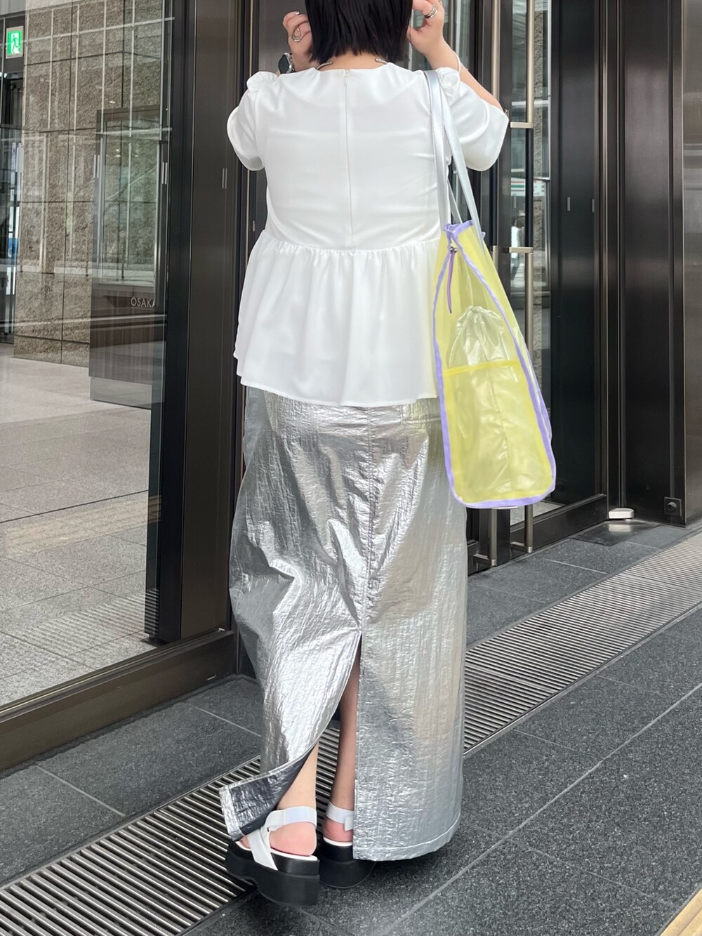 ホワイト系のTシャツ/カットソー、シルバー系のスカート、イエロー系のトートバッグを着用したレディースの春コーディネートの2枚目の写真