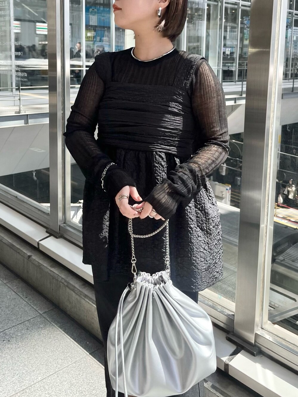 ブラック系のニット/セーター、ブラック系のシャツ/ブラウス、シルバー系のショルダーバッグを着用したレディースの春コーディネートの6枚目の写真