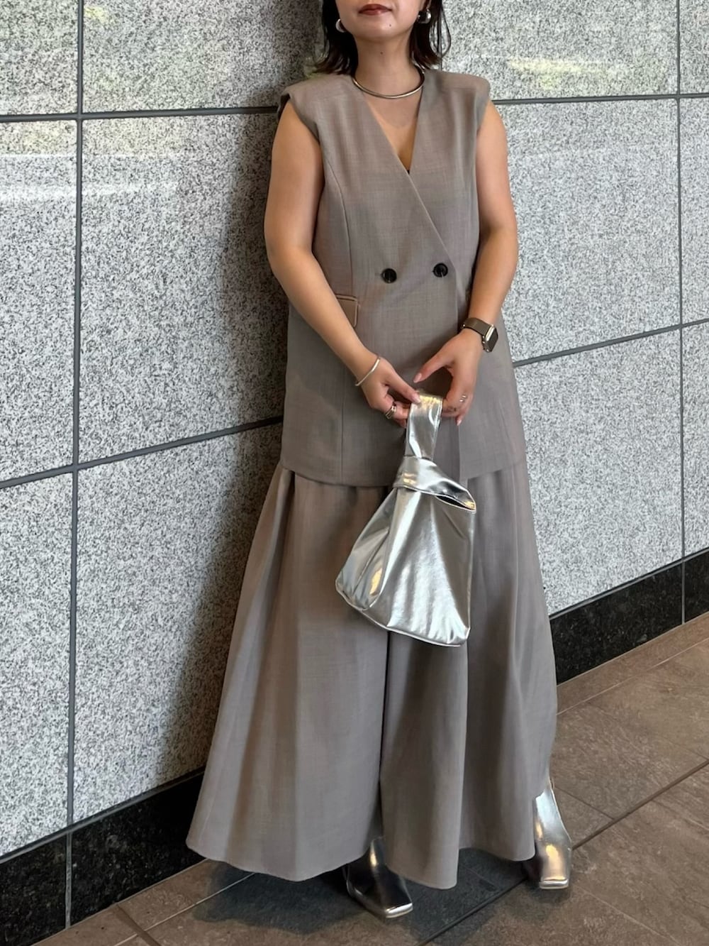 グレー系のワンピース、シルバー系のハンドバッグ、シルバー系のブーツを着用したレディースの夏コーディネートの2枚目の写真