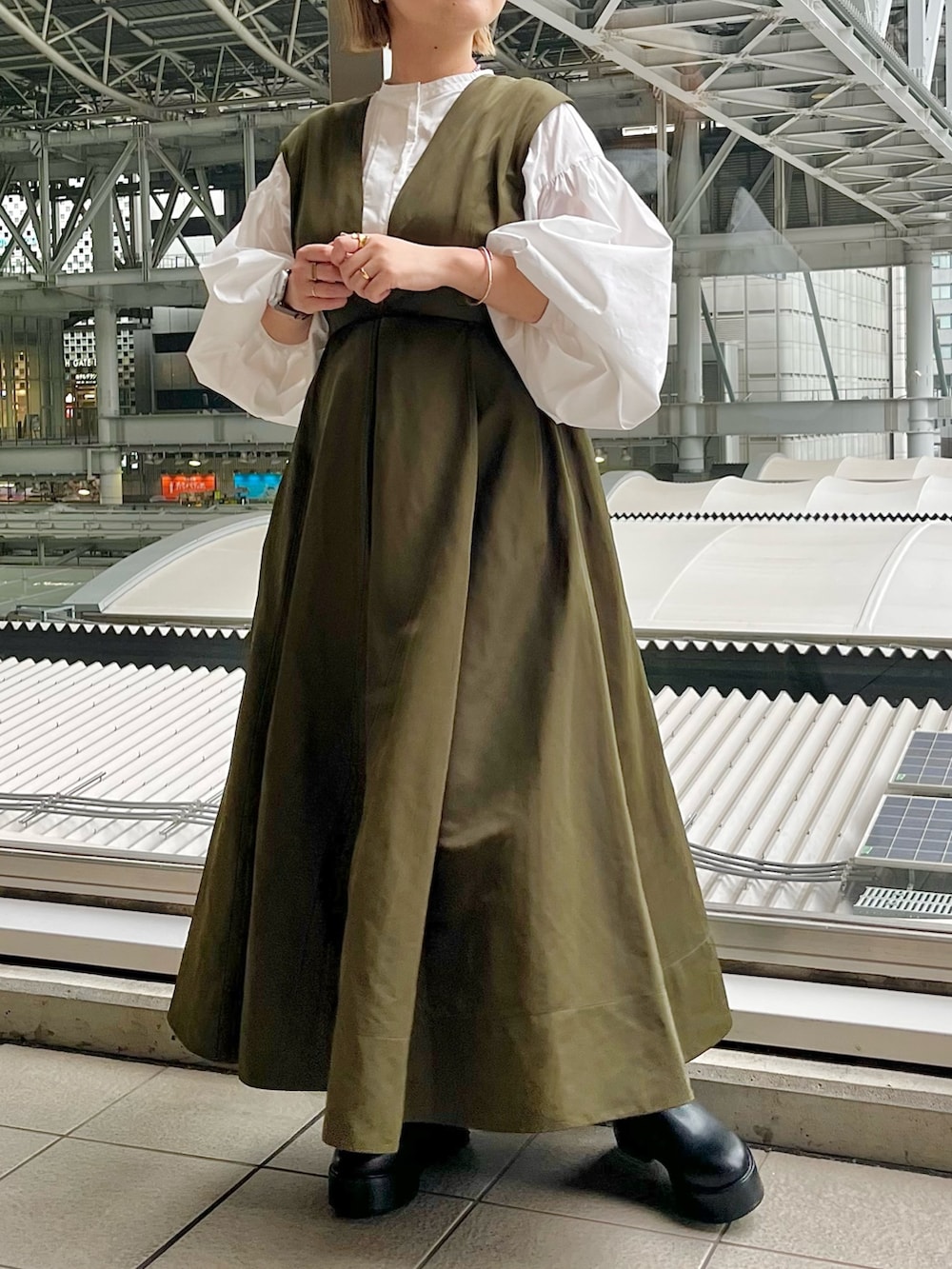 ホワイト系のシャツ/ブラウス、グリーン系のジャンパースカート、ブラック系のブーツを着用したレディースの春コーディネートの4枚目の写真