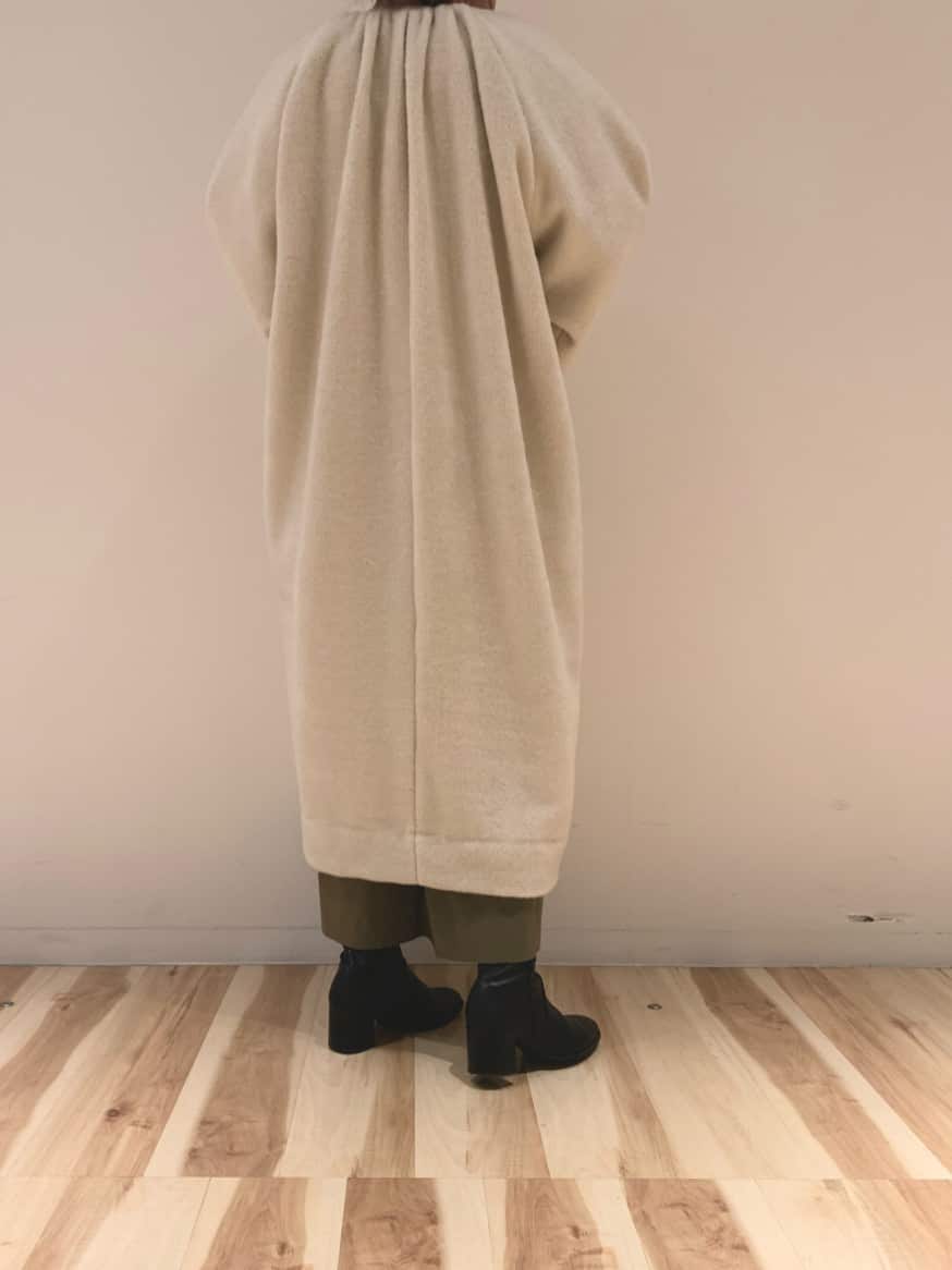 ベージュ系のノーカラーコート、ベージュ系のワンピースを着用したレディースの冬コーディネートの3枚目の写真