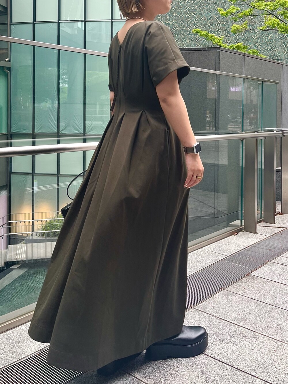 グリーン系のワンピース、ブラック系のブーツ、ブラック系のショルダーバッグを着用したレディースの春コーディネートの4枚目の写真