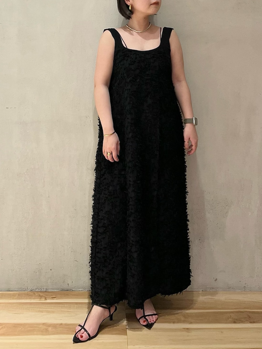 ブラック系のワンピース、ブラック系のタンクトップ、ベージュ系のノーカラーコートを着用したレディースの春コーディネートの6枚目の写真