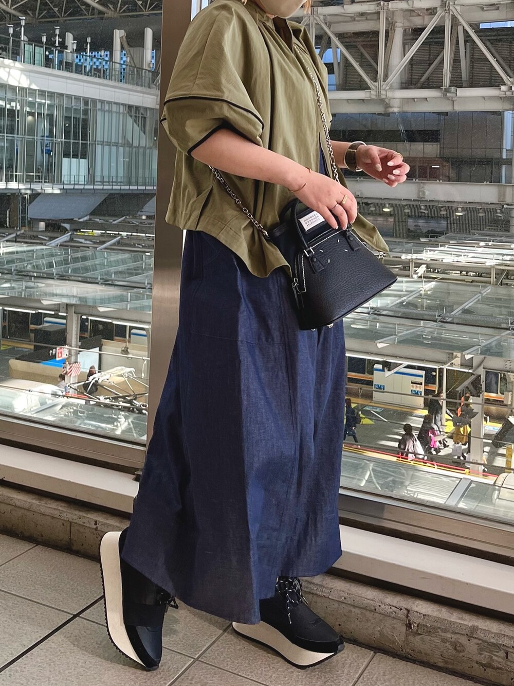 グリーン系のブルゾン、ブルー系のワンピース、ブラック系のスニーカーを着用したレディースの春コーディネートの2枚目の写真