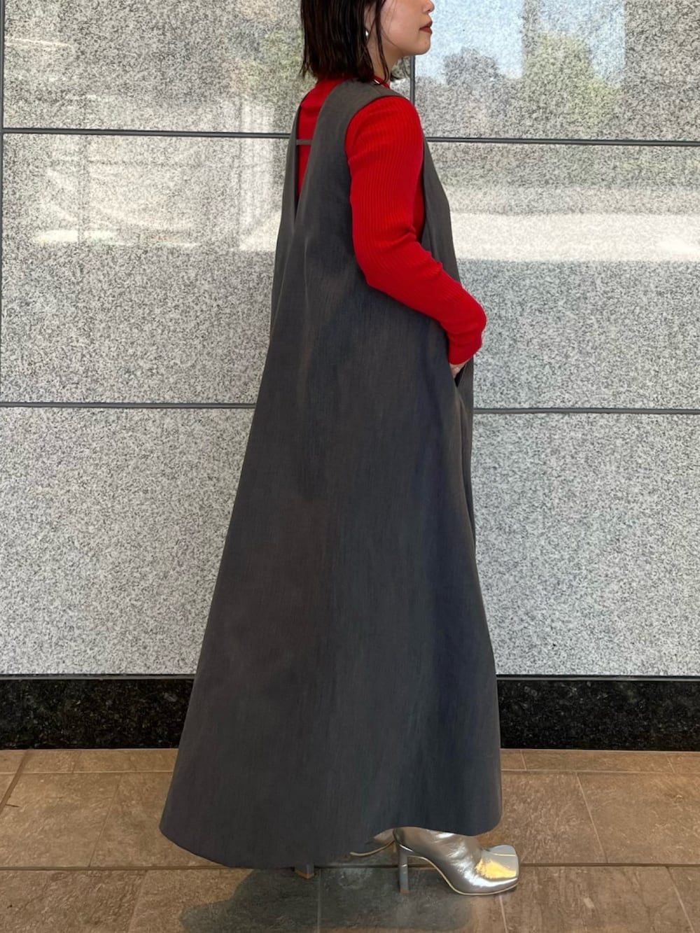 グレー系のジャンパースカート、シルバー系のブーツ、ゴールド系のハンドバッグを着用したレディースの夏コーディネートの3枚目の写真