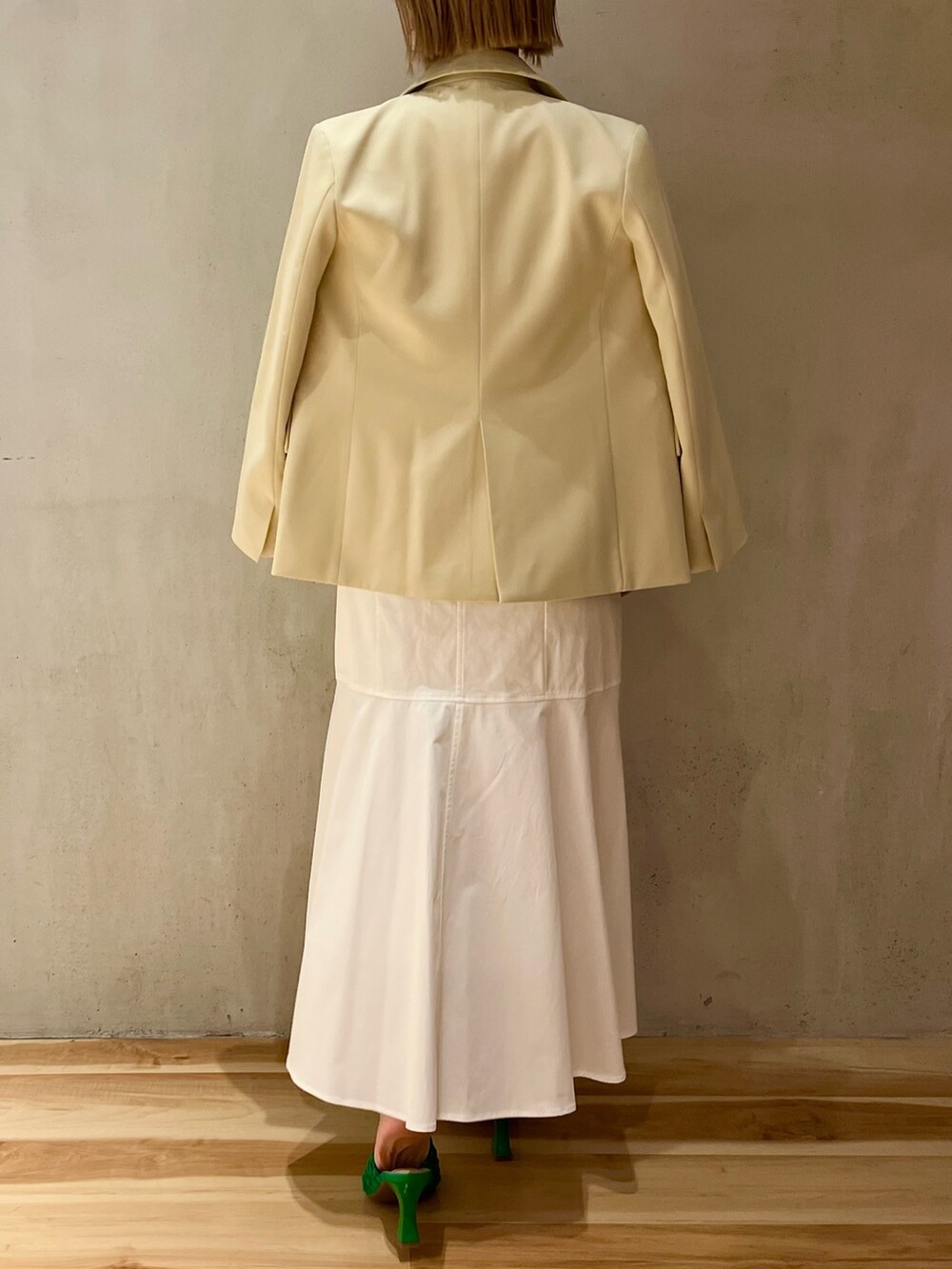 イエロー系のテーラードジャケット、ホワイト系のニット/セーター、ホワイト系のスカートを着用したレディースの冬コーディネートの3枚目の写真