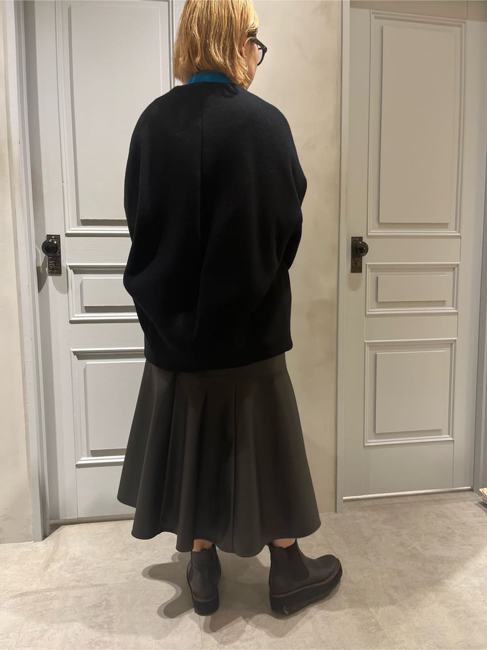 ブラック系のスカート、ブラック系のノーカラーコート、ブルー系のニット/セーターを着用したレディースの秋コーディネートの4枚目の写真