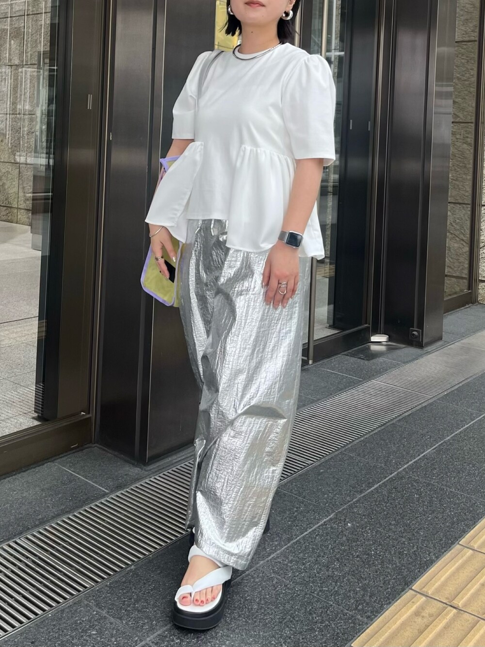 ホワイト系のTシャツ/カットソー、シルバー系のスカート、イエロー系のトートバッグを着用したレディースの春コーディネートの4枚目の写真