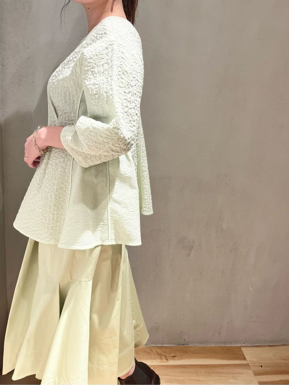 ベージュ系のステンカラーコート、グリーン系のスカート、グリーン系のシャツ/ブラウスを着用したレディースの春コーディネートの5枚目の写真