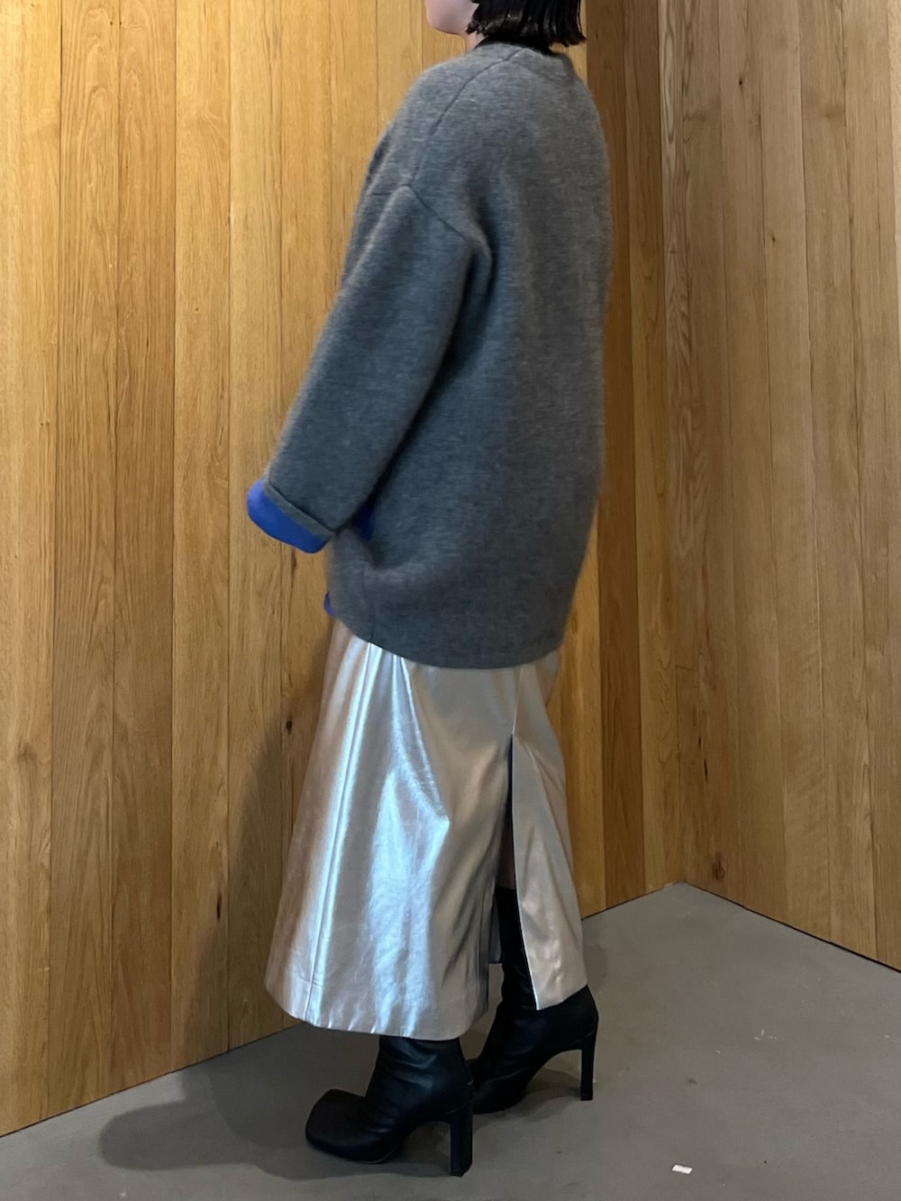 グレー系のカーディガン/ボレロ、シルバー系のスカート、ブラック系のブーツを着用したレディースの秋コーディネートの2枚目の写真