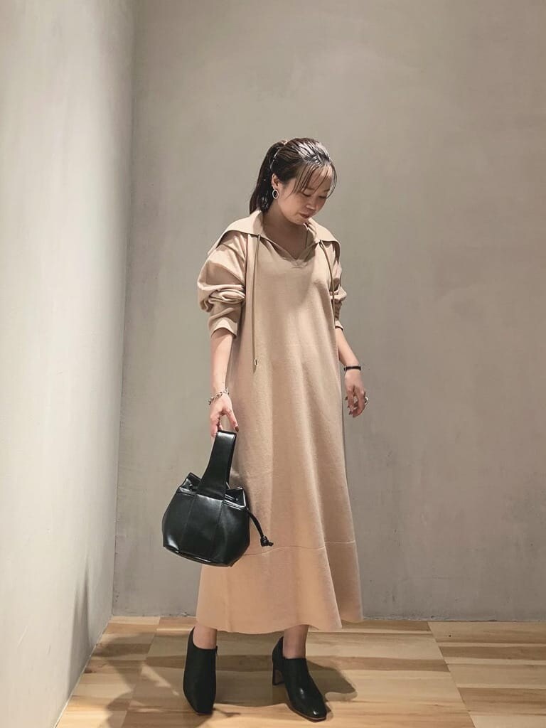 ベージュ系のワンピース、ブラック系のブーツ、ブラック系のハンドバッグを着用したレディースの秋コーディネートの2枚目の写真