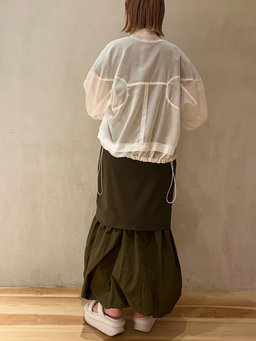 ホワイト系のサンダル、ホワイト系のブルゾン、グリーン系のワンピースを着用したレディースの冬コーディネートの3枚目の写真