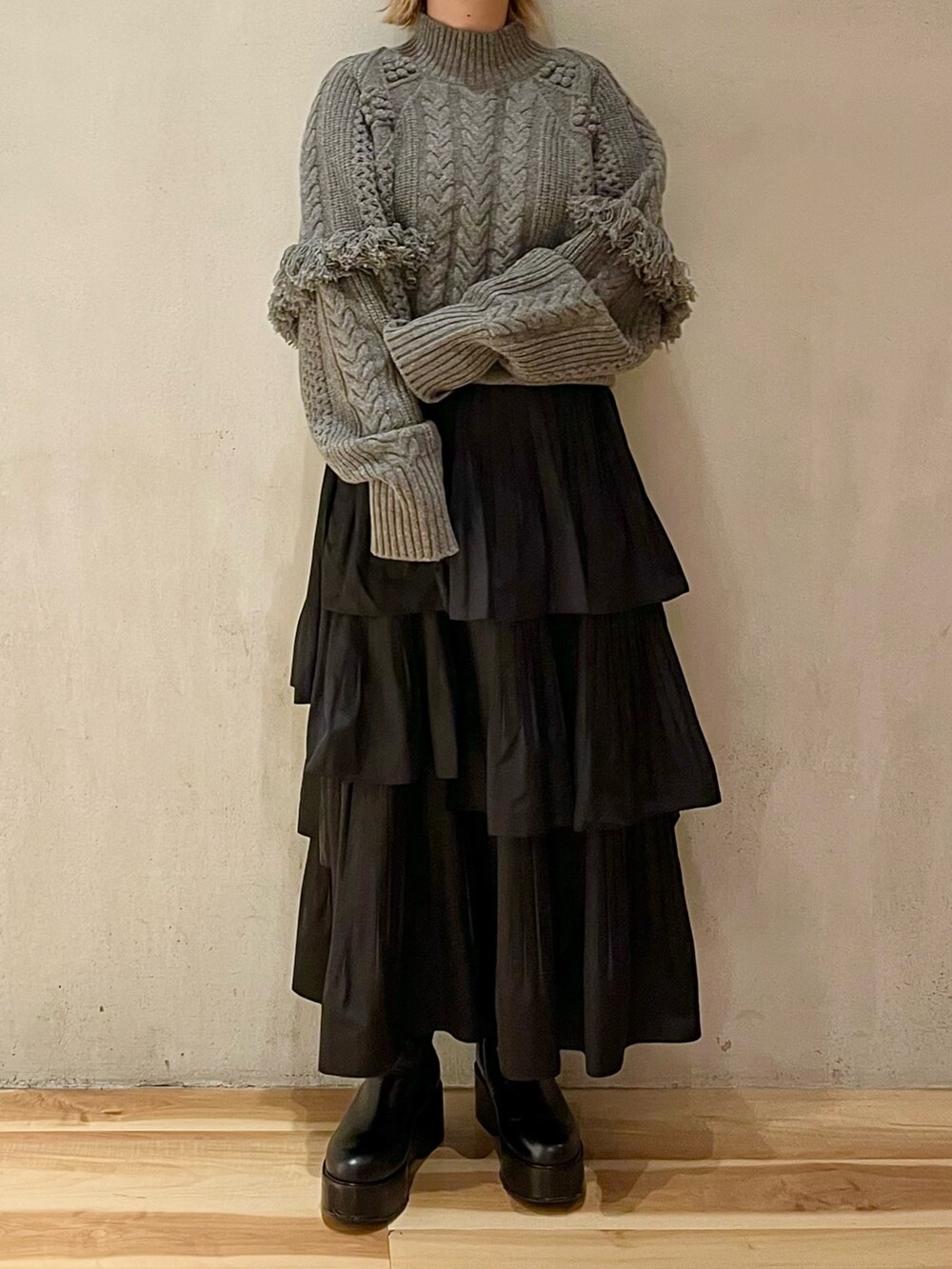 グレー系のニット/セーター、ブラック系のスカート、ブラック系のブーツを着用したレディースの秋コーディネートの3枚目の写真
