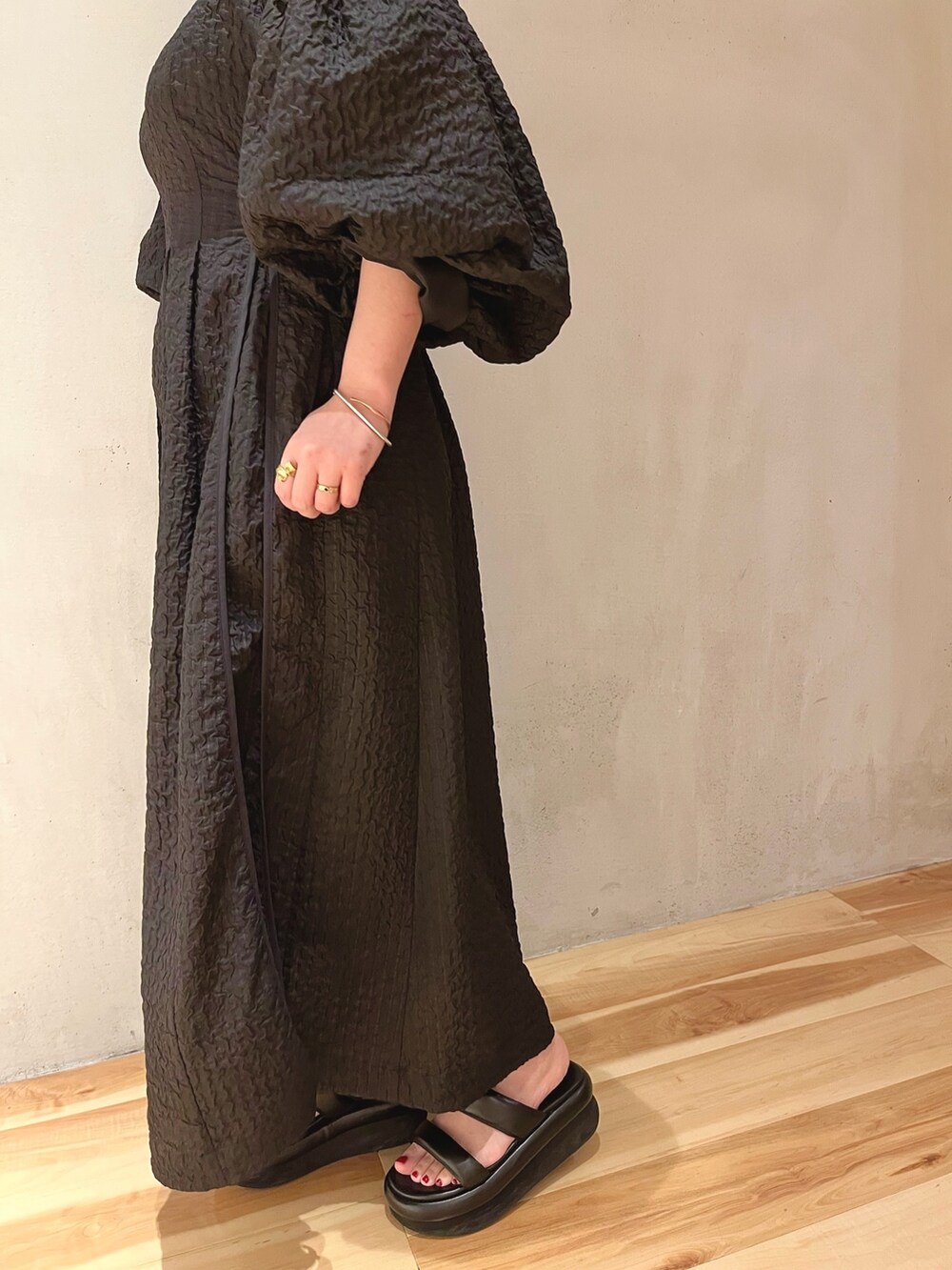 ブラック系のサンダル、ブラック系のワンピース、ゴールド系のネックレスを着用したレディースの冬コーディネートの7枚目の写真