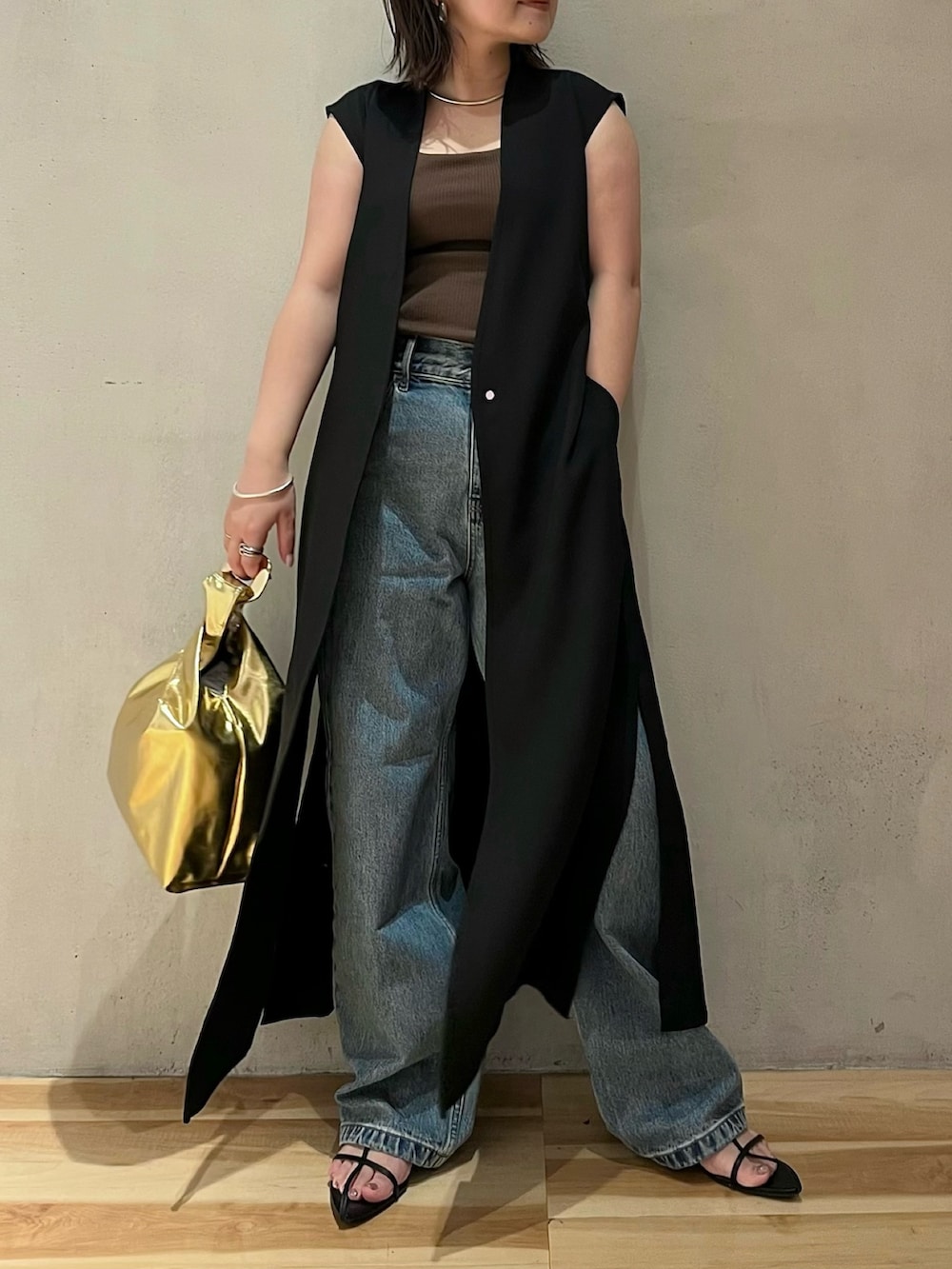 ブラック系のベスト、ブラウン系のタンクトップ、ブルー系のデニムパンツを着用したレディースの夏コーディネートの2枚目の写真