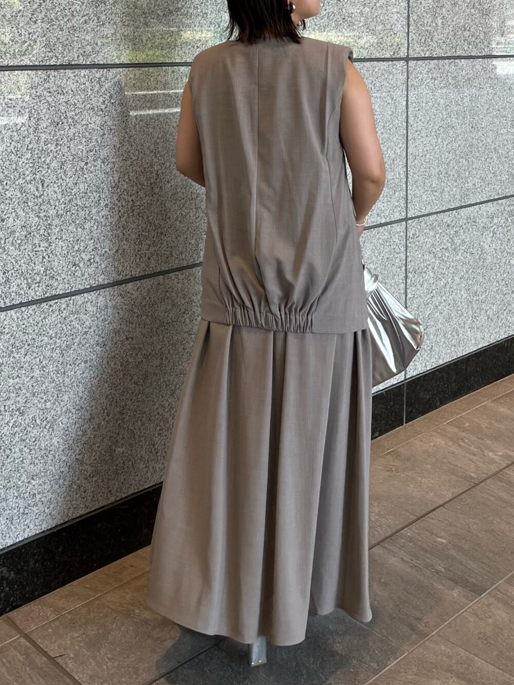 グレー系のワンピース、シルバー系のハンドバッグ、シルバー系のブーツを着用したレディースの夏コーディネートの5枚目の写真