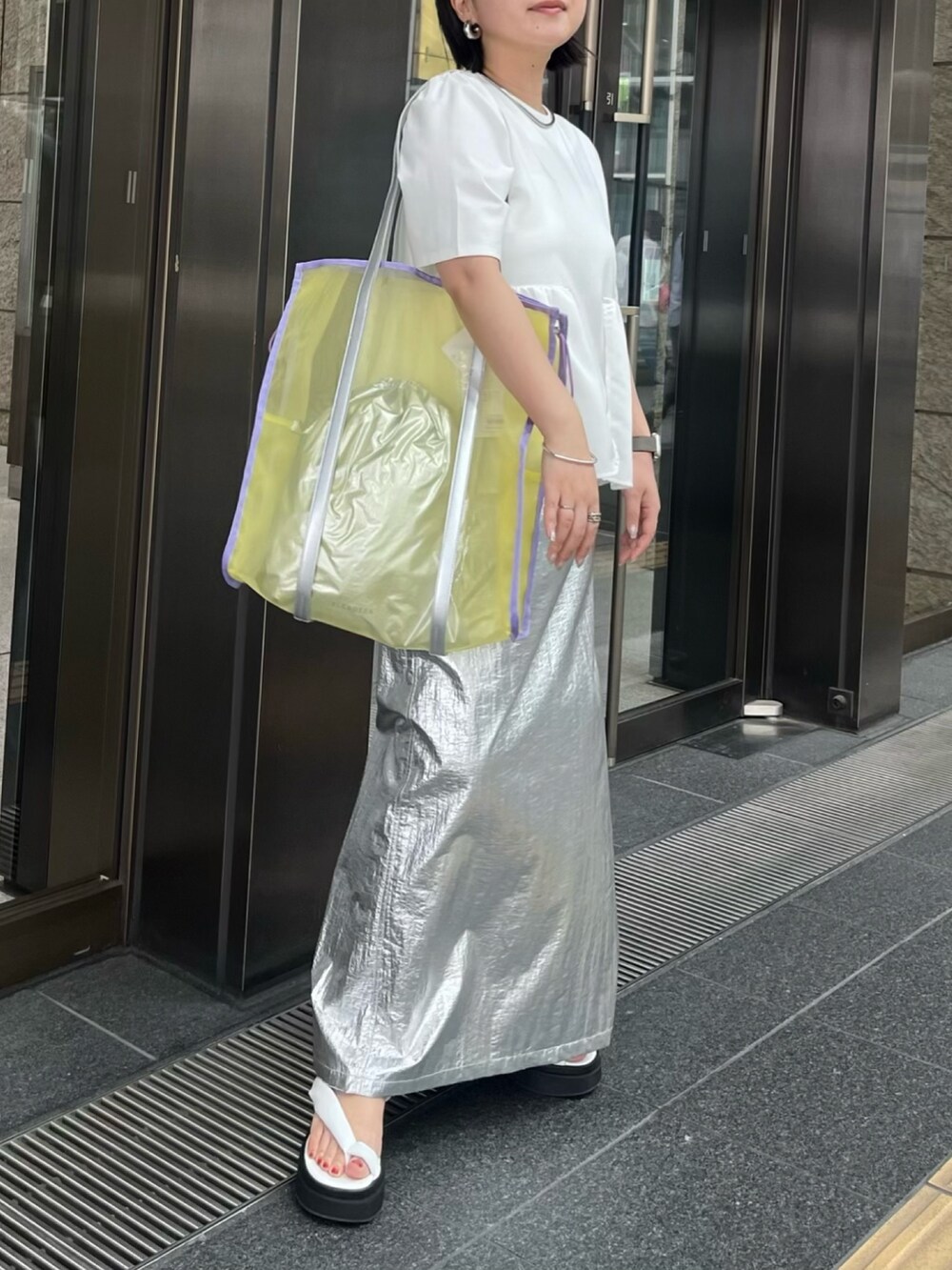 ホワイト系のTシャツ/カットソー、シルバー系のスカート、イエロー系のトートバッグを着用したレディースの春コーディネートの5枚目の写真
