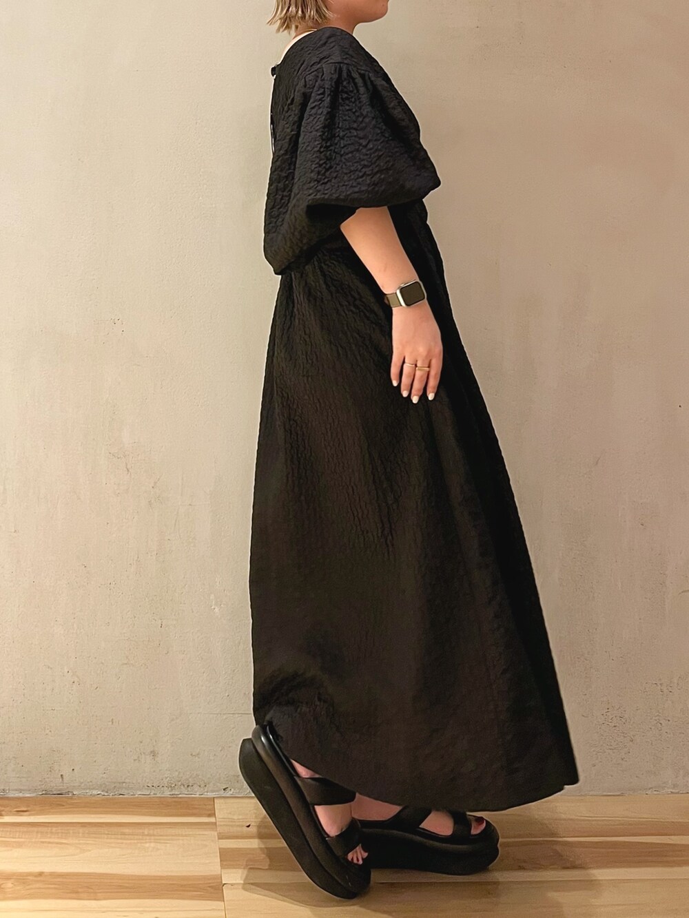 ブラック系のサンダル、ブラック系のワンピース、ゴールド系のネックレスを着用したレディースの冬コーディネートの2枚目の写真