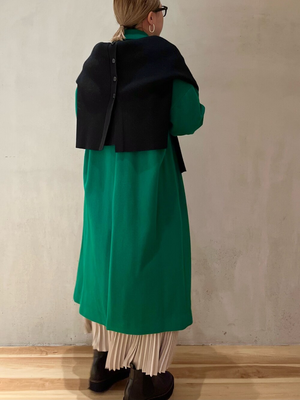 グリーン系のチェスターコート、ブラック系のカーディガン/ボレロ、ベージュ系のワンピースを着用したレディースの冬コーディネートの3枚目の写真