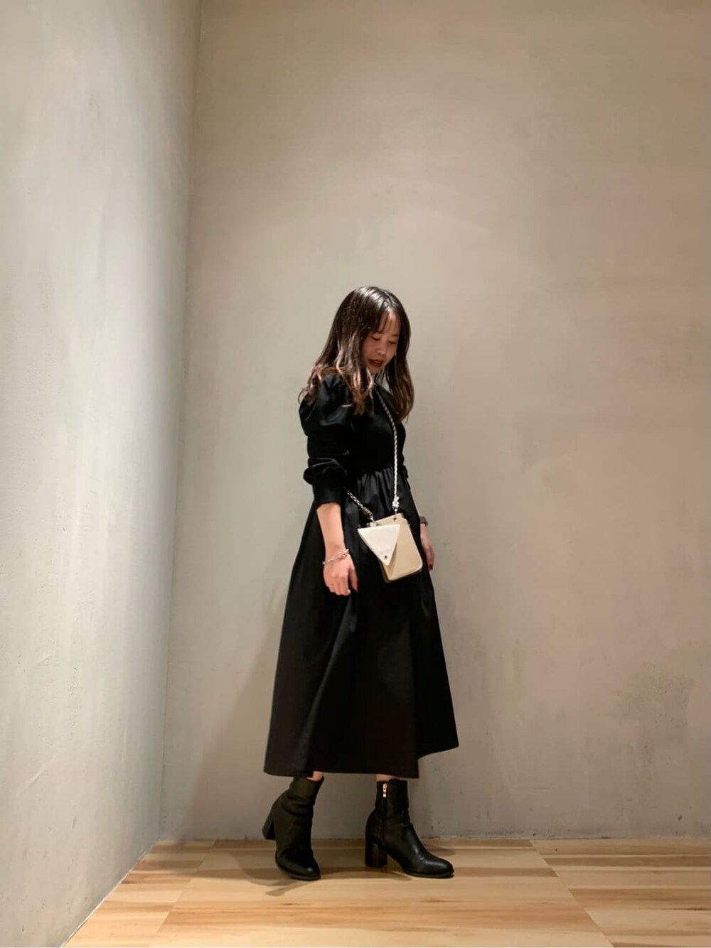 ベージュ系のショルダーバッグ、ブラック系のワンピースを着用したレディースの秋コーディネートの2枚目の写真