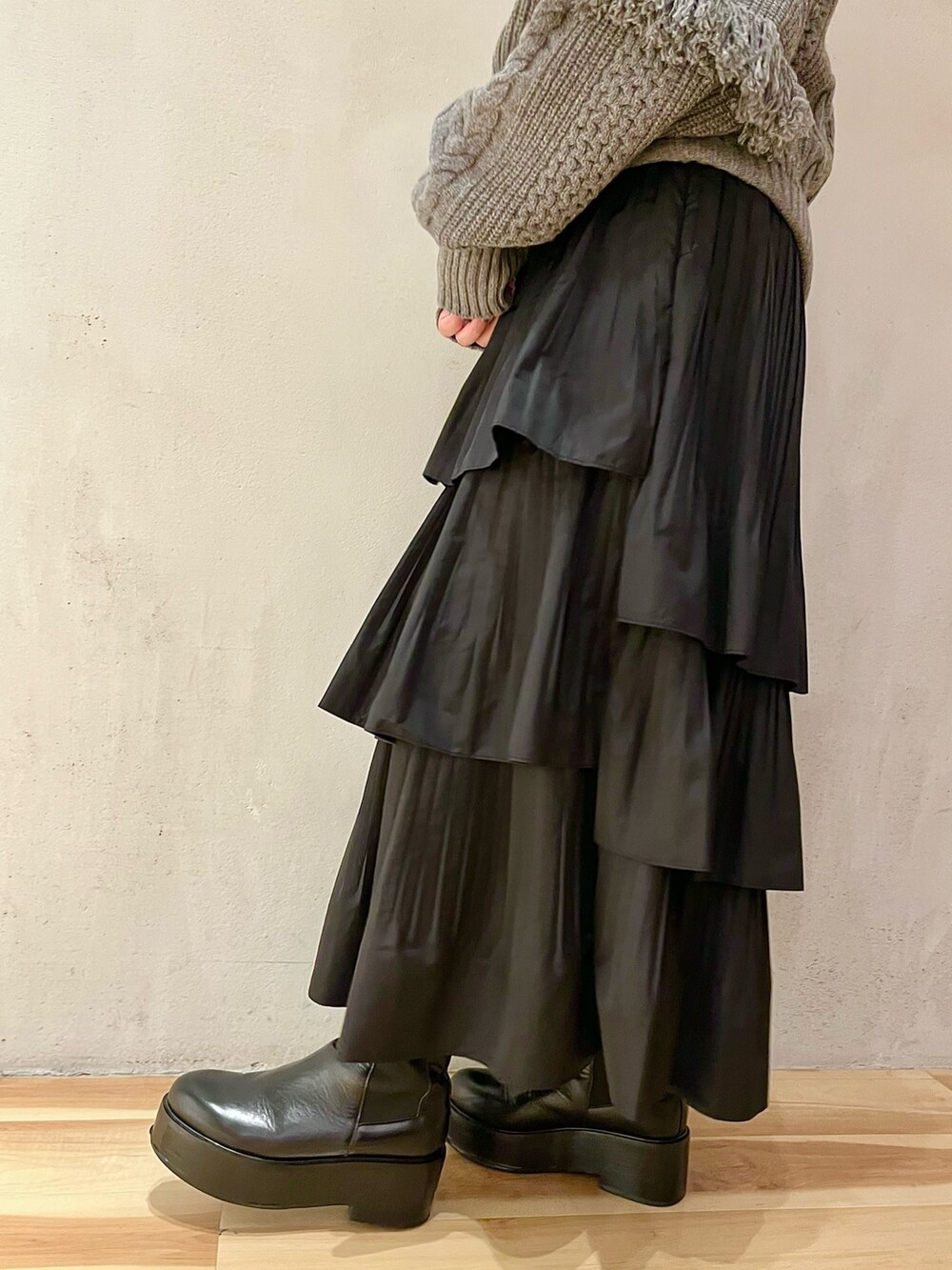 グレー系のニット/セーター、ブラック系のスカート、ブラック系のブーツを着用したレディースの秋コーディネートの8枚目の写真