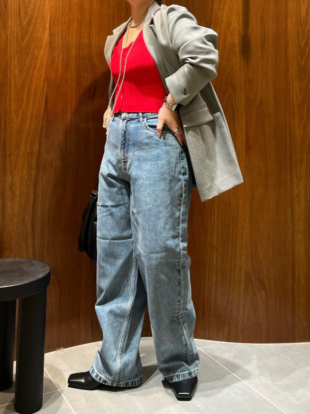 ブラック系のテーラードジャケット、レッド系のカーディガン/ボレロ、ブラック系のハンドバッグを着用したレディースの秋コーディネートの3枚目の写真