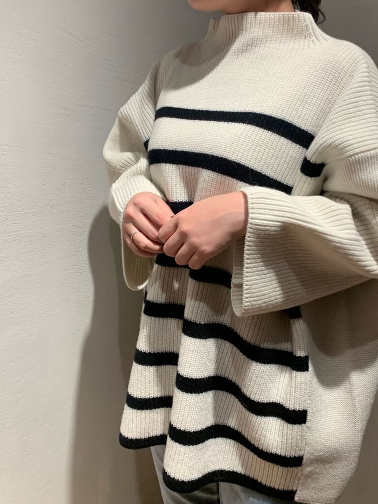 ブルー系のデニムパンツ、ブラック系のブーツ、ホワイト系のニット/セーターを着用したレディースの秋コーディネートの5枚目の写真
