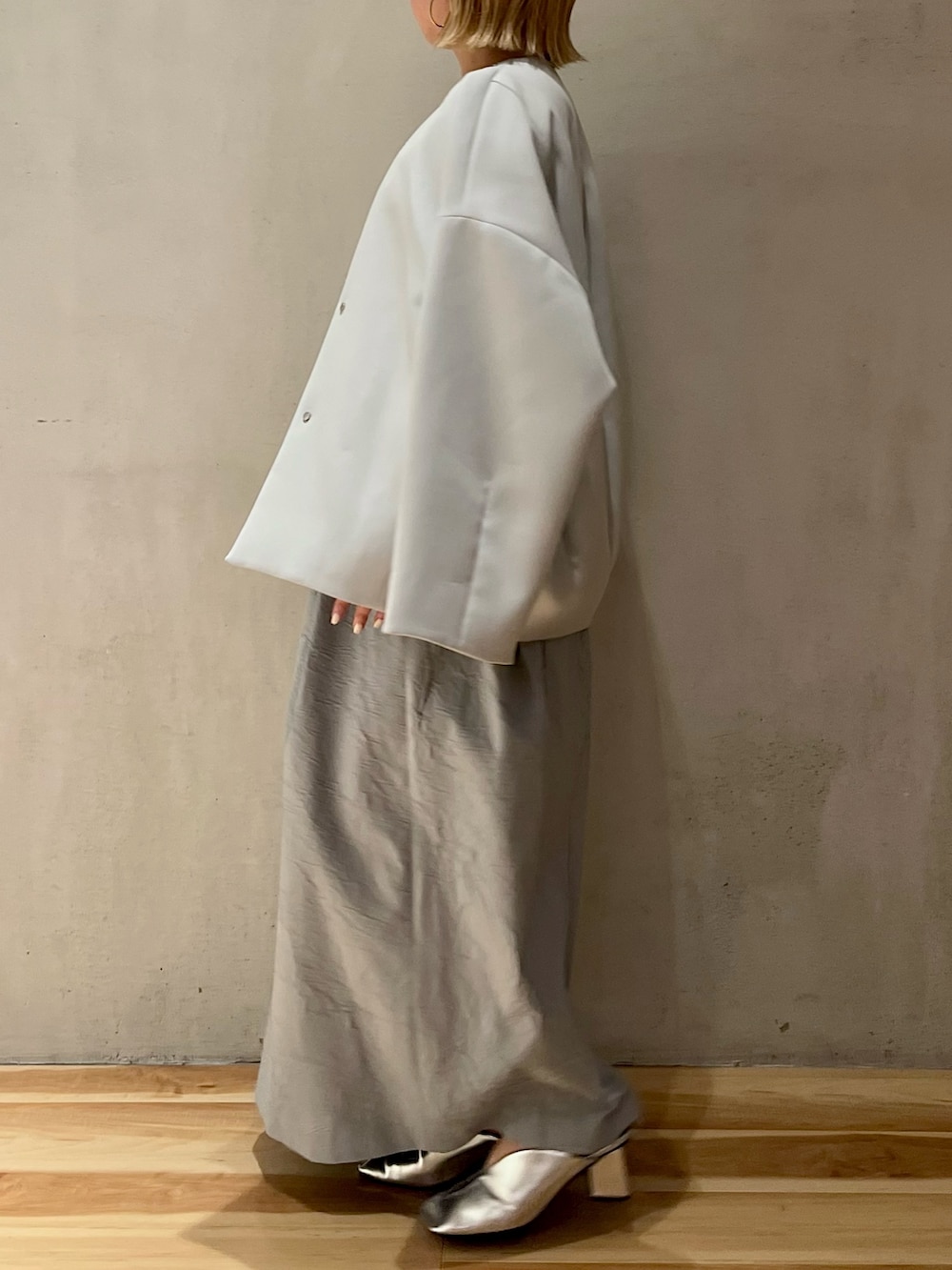 ブルー系のノーカラーコート、シルバー系のパンプス、ブルー系のワンピースを着用したレディースの冬コーディネートの2枚目の写真