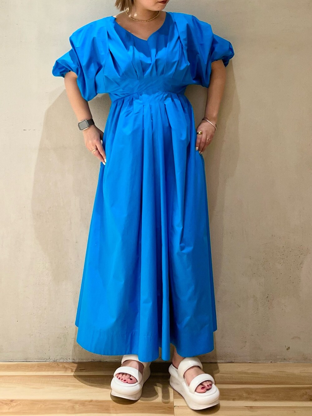 ブルー系のワンピース、ホワイト系のサンダル、ゴールド系のネックレスを着用したレディースの冬コーディネートの4枚目の写真