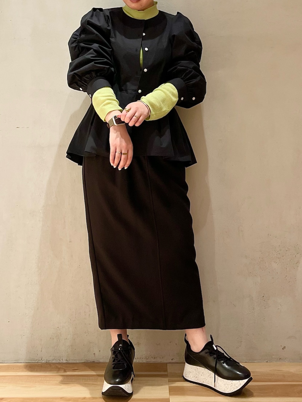 ブラック系のシャツ/ブラウス、グリーン系のニット/セーター、ブラック系のスカートを着用したレディースの冬コーディネートの3枚目の写真