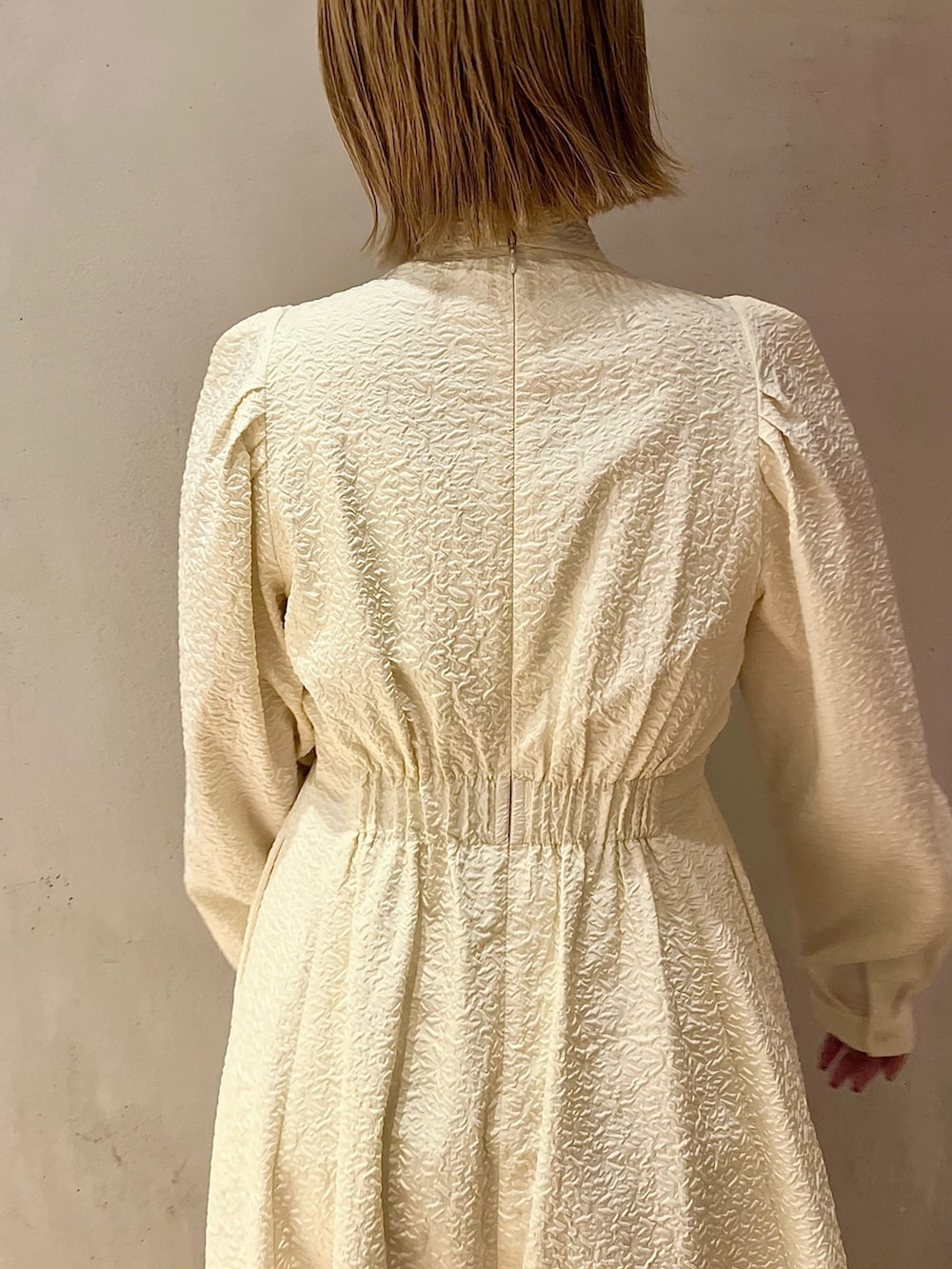 ホワイト系のノーカラージャケット、ホワイト系のワンピース、ベージュ系のブーツを着用したレディースの秋コーディネートの9枚目の写真