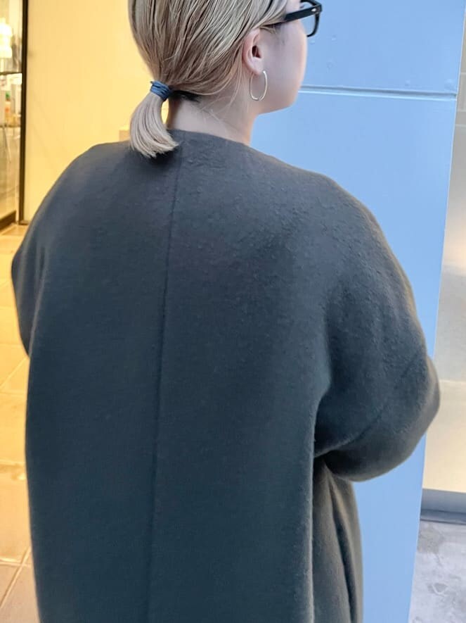 ホワイト系のショルダーバッグ、グリーン系のノーカラーコート、ベージュ系のワンピースを着用したレディースの秋コーディネートの5枚目の写真