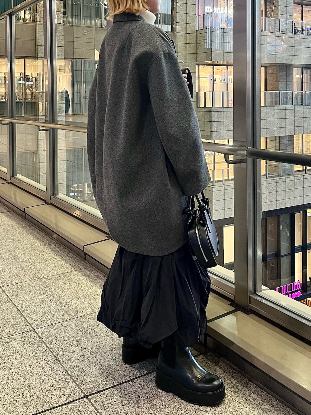 ブラック系のスカート、ブラック系のブーツ、ブラック系のハンドバッグを着用したレディースの冬コーディネートの4枚目の写真