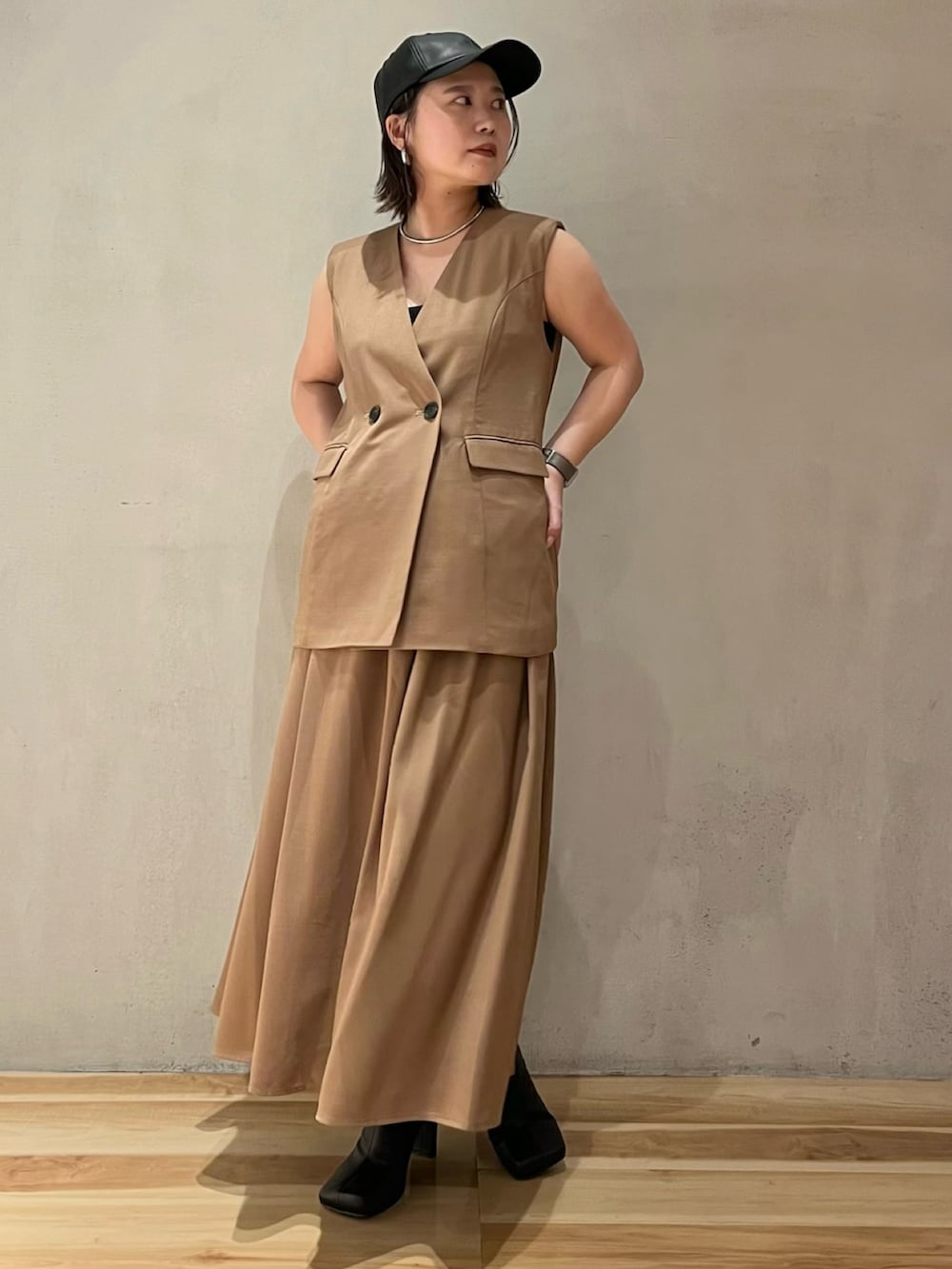 ベージュ系のワンピース、ブラック系のブーツ、ブラック系のキャップを着用したレディースの夏コーディネートの4枚目の写真