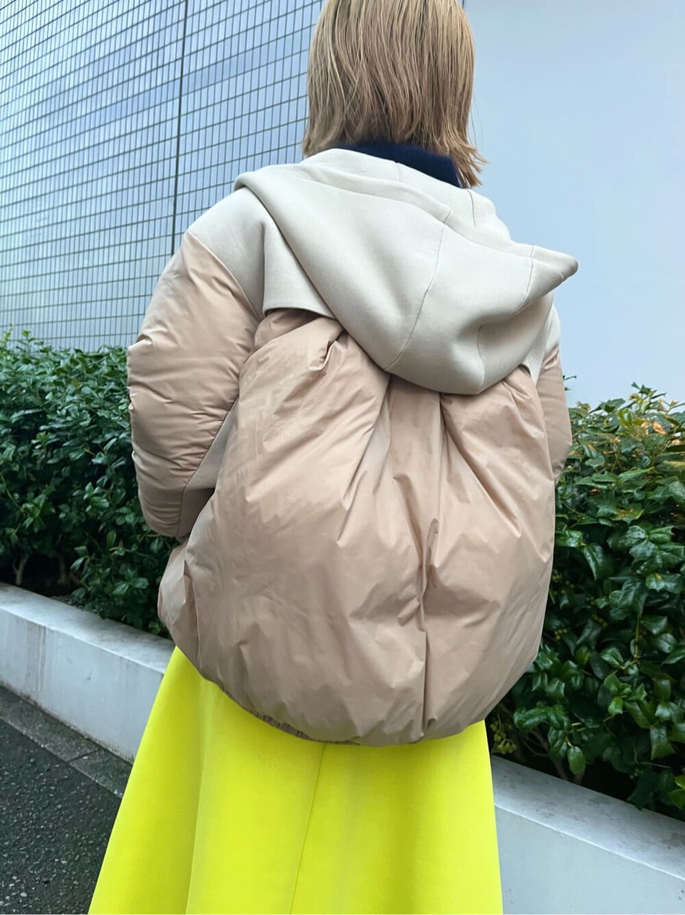 ベージュ系のダウンジャケット/コート、ブルー系のニット/セーター、イエロー系のスカートを着用したレディースの秋コーディネートの6枚目の写真