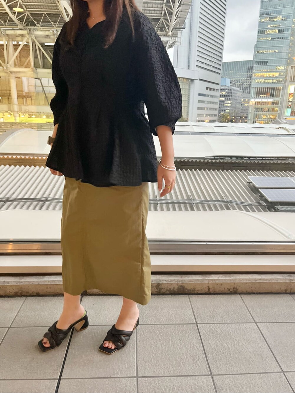 ブラック系のシャツ/ブラウス、ブラック系のサンダル、ベージュ系のスカートを着用したレディースの春コーディネートの4枚目の写真