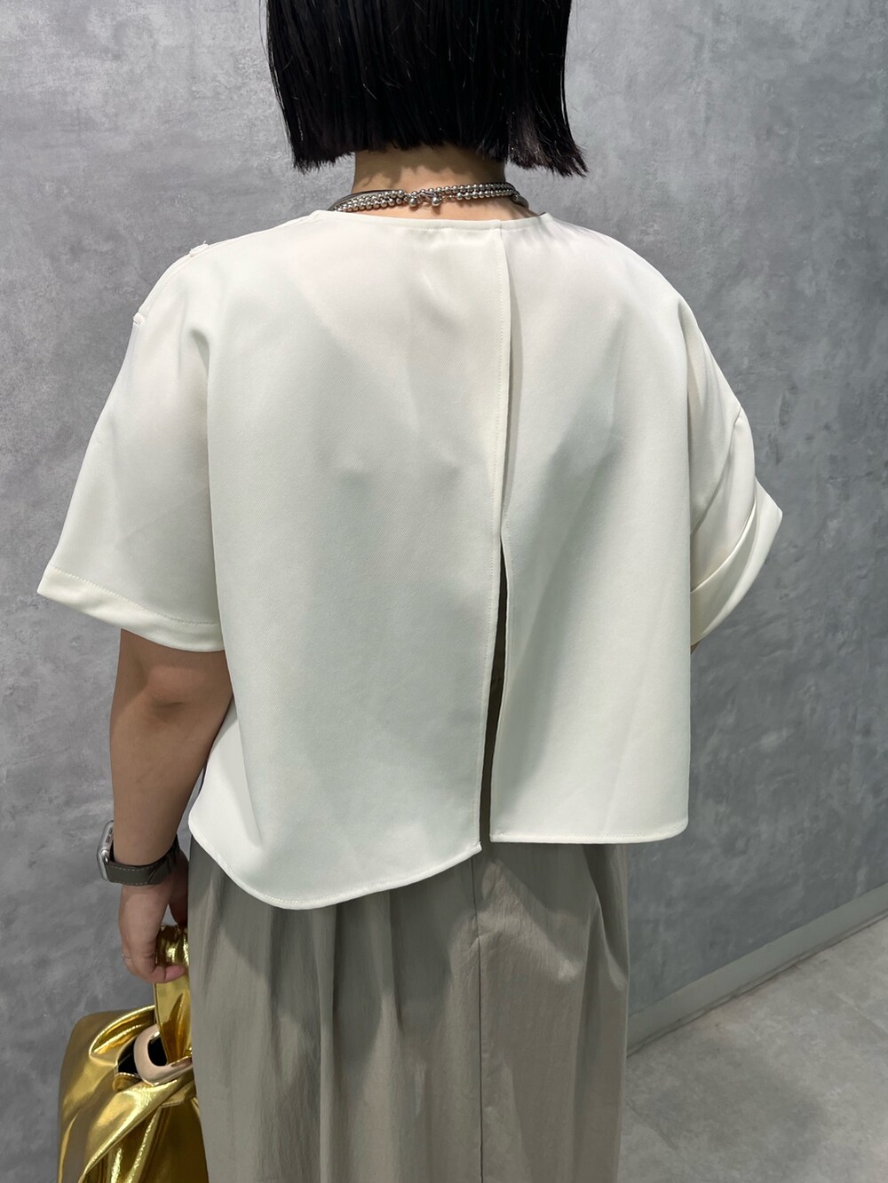 ベージュ系のワンピース、ゴールド系のハンドバッグを着用したレディースの夏コーディネートの6枚目の写真