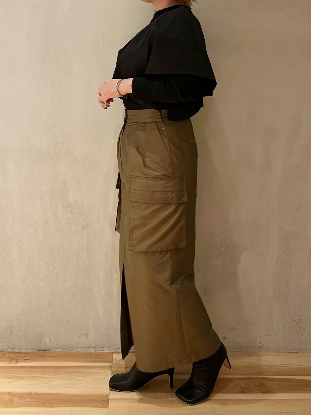 ブラウン系のスカート、ブラック系のブーツ、ブラック系のニット/セーターを着用したレディースの春コーディネートの6枚目の写真