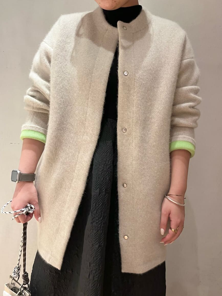 ベージュ系のショルダーバッグ、ホワイト系のカーディガン/ボレロ、ブラウン系のブーツを着用したレディースの秋コーディネートの5枚目の写真