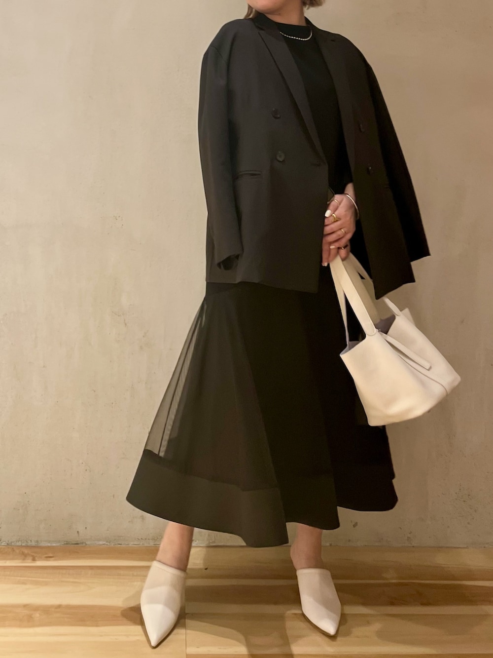 ブラック系のテーラードジャケット、ブラック系のワンピース、シルバー系のネックレスを着用したレディースの冬コーディネートの3枚目の写真